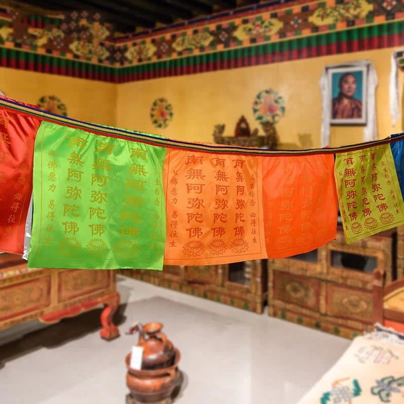 Handprinted Buddhist prayer flags displayed indoors in traditional Tibetan room setting