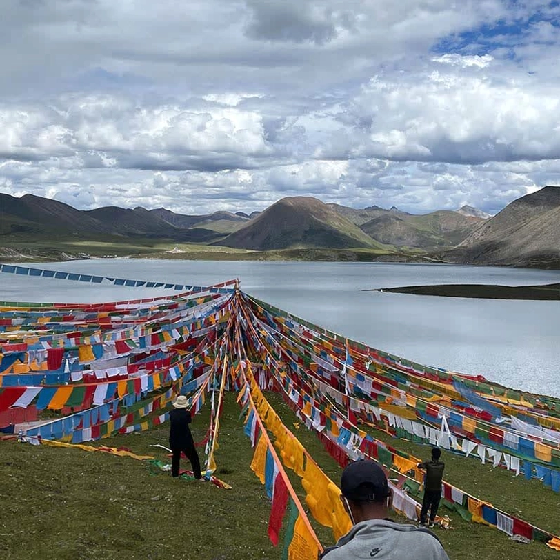 Tibetan prayer flags installation at high altitude lakeside landscape with multiple colorful flag rows