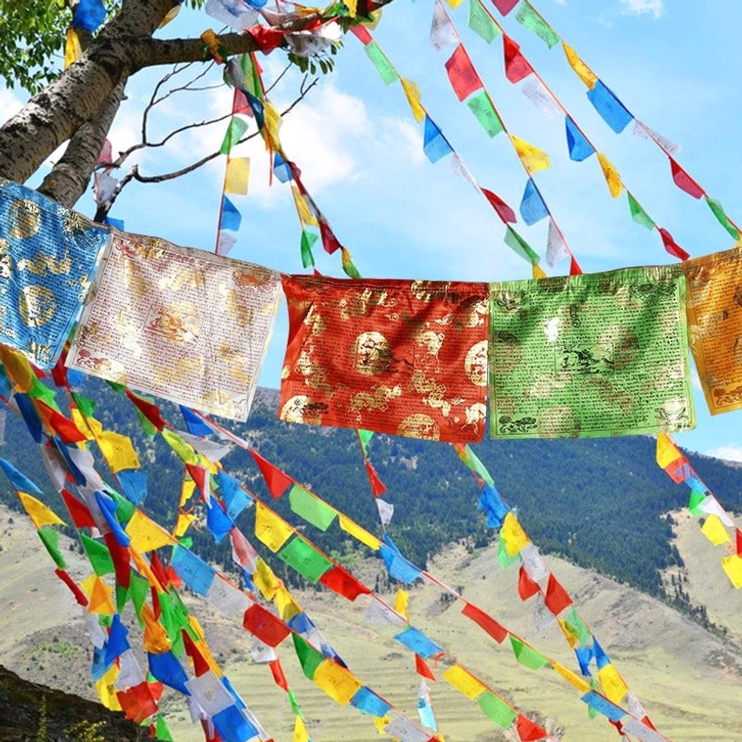 Tibetan prayer flags hanging outdoors in mountain wilderness - five color windhorse and dragon blessing flags strung among tree branches