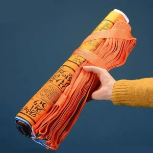 Rolled Tibetan prayer flag bundle with orange securing strap and visible Tibetan pattern prints