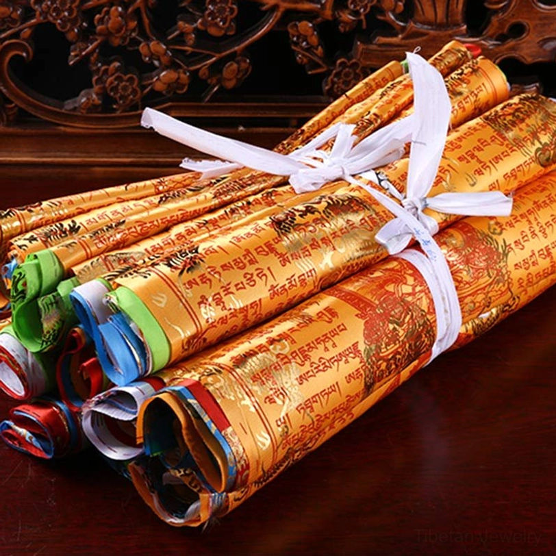 Rolled tibetan prayer flag bundle with golden foil printed Buddhist scripture, tied with white ribbon on wooden carved table