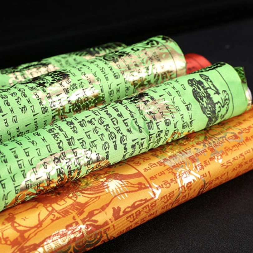 Rolled Tibetan prayer flags close-up - gold foil dragon motifs and sacred Tibetan script on multicolor fabrics