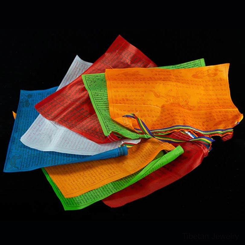 Scattered loose Tibetan prayer flags in multiple colors blue red green showing colorful hanging cords and tassels