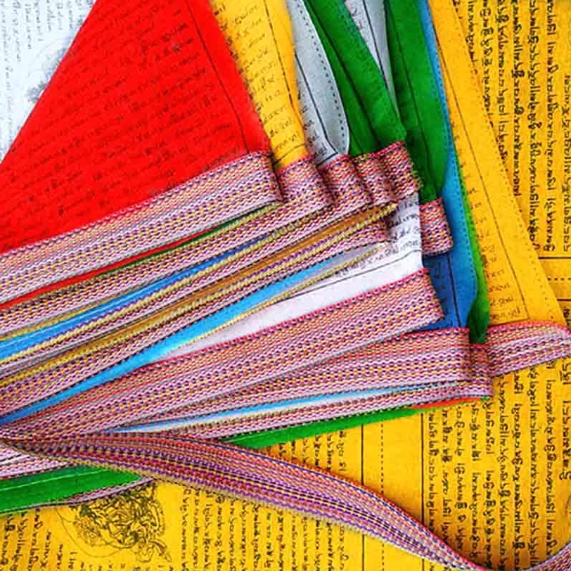 Neatly stacked Tibetan five element prayer flags in traditional colors with woven edge trim flat lay overhead shot