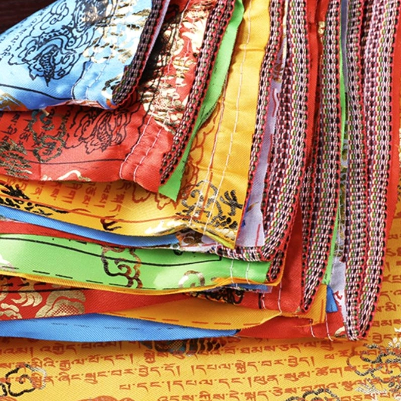 Stacked colorful Tibetan prayer flags - woven checkered hanging edges visible on traditional five-color blessing flags