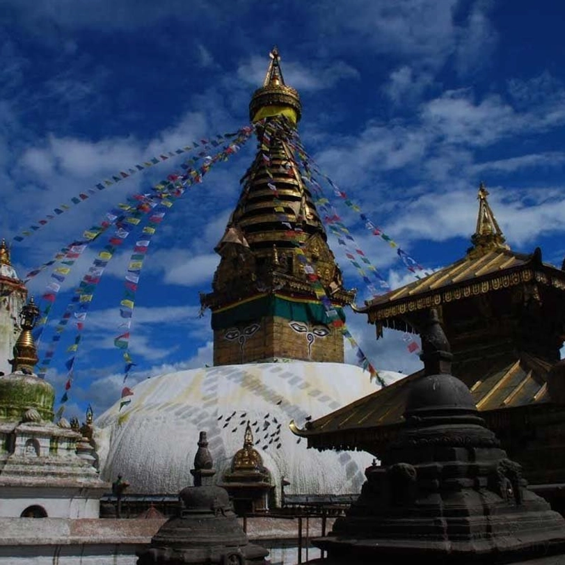 Multiple prayer flags displayed across Buddhist temple complex with traditional architecture and stupas