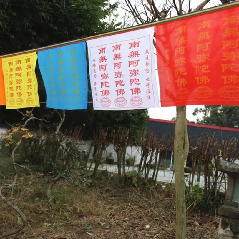 Multi-color Buddhist prayer flag string mounted on wooden pole in rural garden