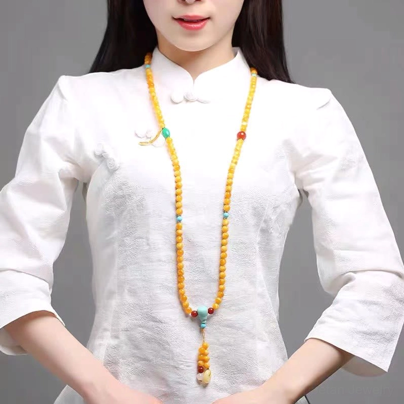 Model wearing long Tibetan amber mala necklace with white traditional shirt demonstrating daily ethnic spiritual styling