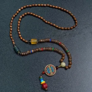 Close-up of Tibetan Buddhist prayer bead necklace with enamel mantra pendant and wooden beads on dark background