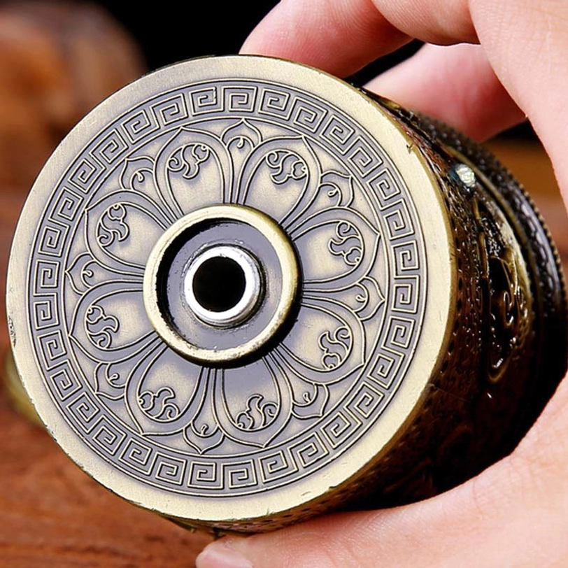 Tibetan prayer wheel bottom view showing lotus flower engraving and geometric border design