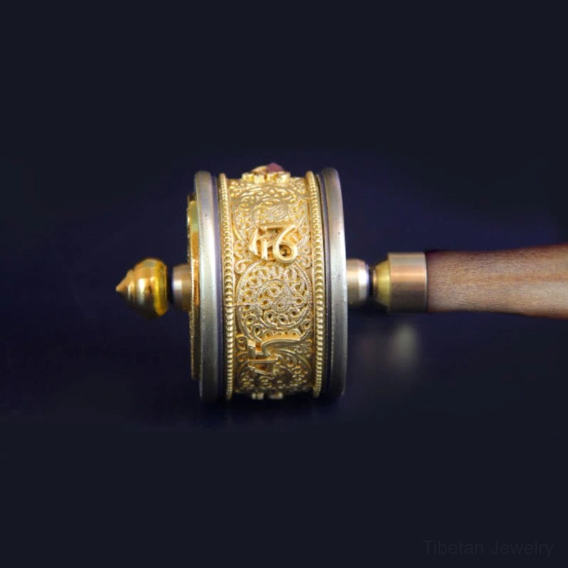 Close-up front view of Tibetan prayer wheel displaying intricate embossed patterns, hand-engraved Six True Words, and natural wood grain grip