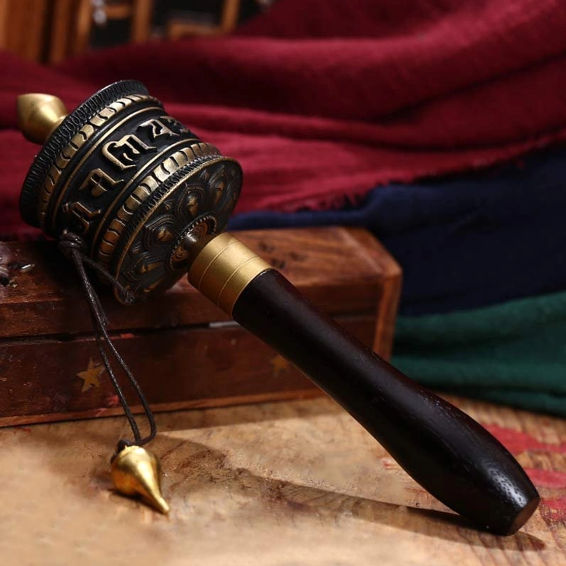 Close-up detail of golden tibetan prayer wheel head showing lotus petal relief carvings and polished copper surface