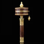 Tibetan prayer wheel with copper body and ornate gold accents front view