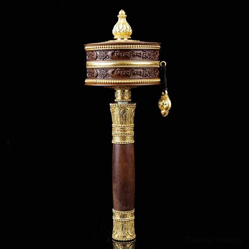 Tibetan prayer wheel with copper body and ornate gold accents front view