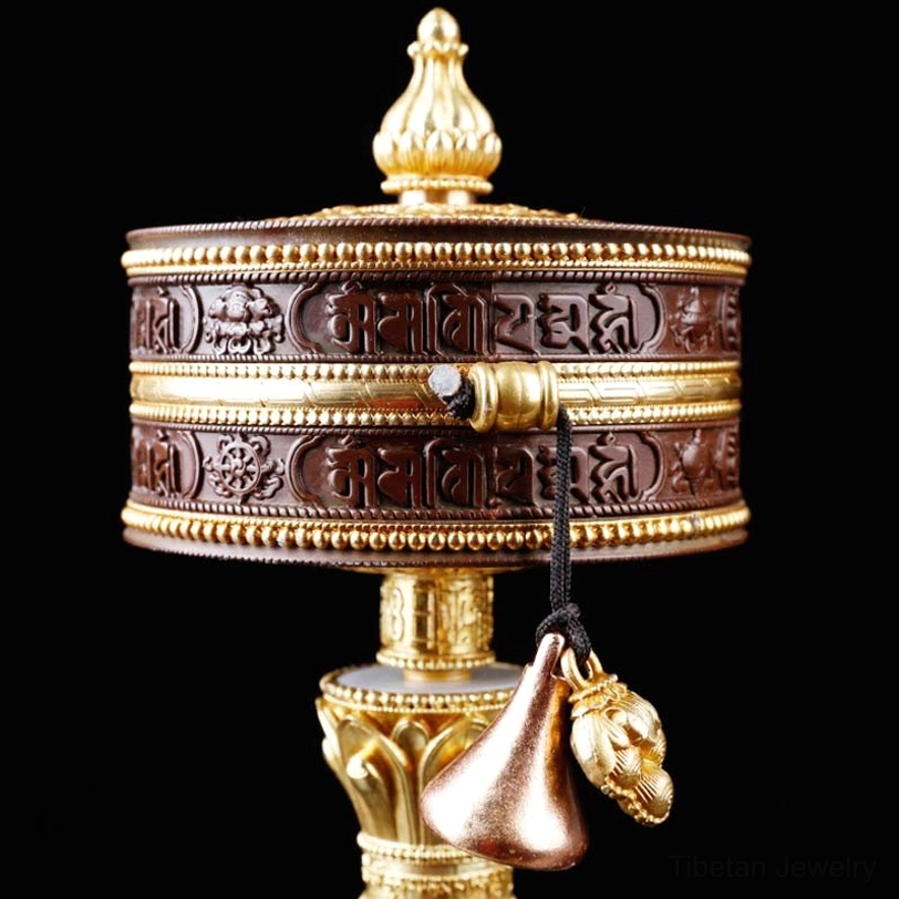 Close-up of engraved Tibetan sutra cylinder with gold decorative bands
