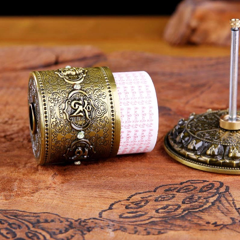 Flat lay side view of Tibetan prayer wheel separated base and barrel with red scripture insert on wooden surface