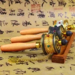 Tibetan hand prayer wheel with Om Mani Padme Hum engraved on wooden handles displayed in overhead flat lay view