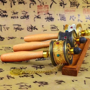 Tibetan hand prayer wheel with Om Mani Padme Hum engraved on wooden handles displayed in overhead flat lay view