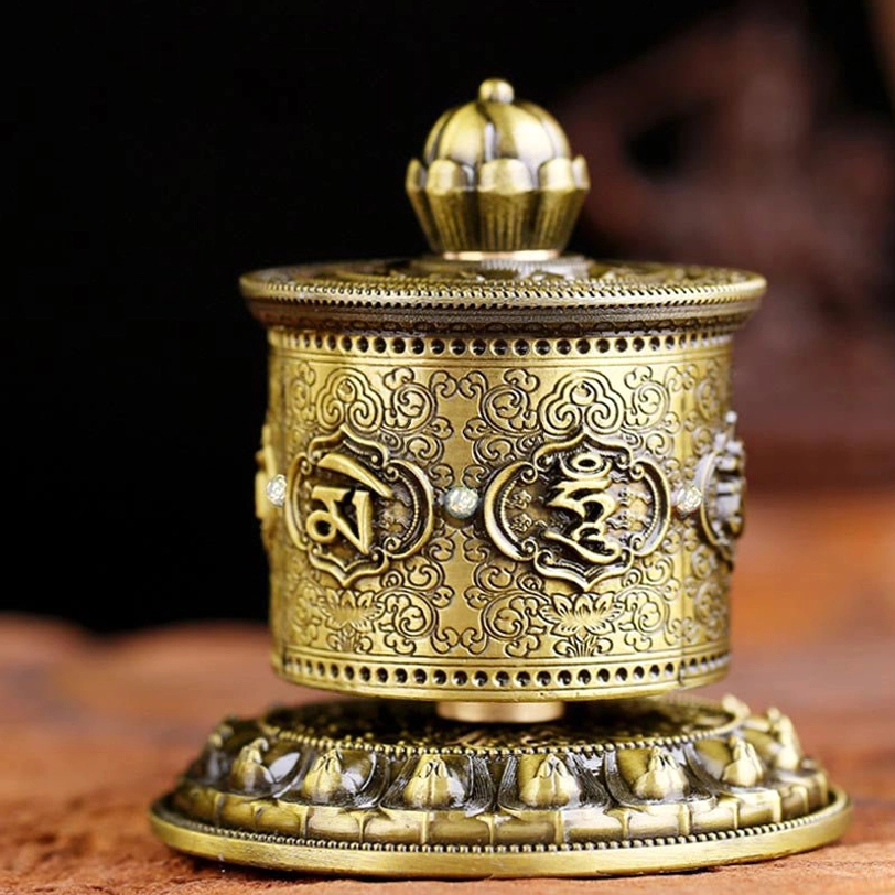 Red Tibetan prayer wheel decoration front view showing embossed mantra and decorative studs on dark background
