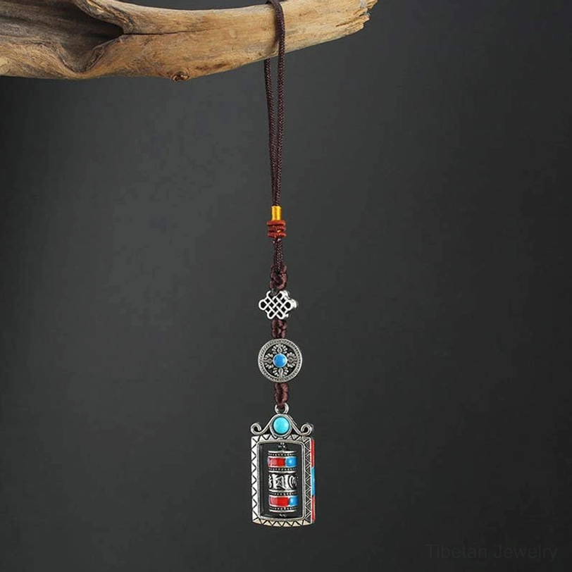 Six true words prayer wheel keychain with inlaid red round stone, fixed prayer tube design, silver alloy frame on wooden background