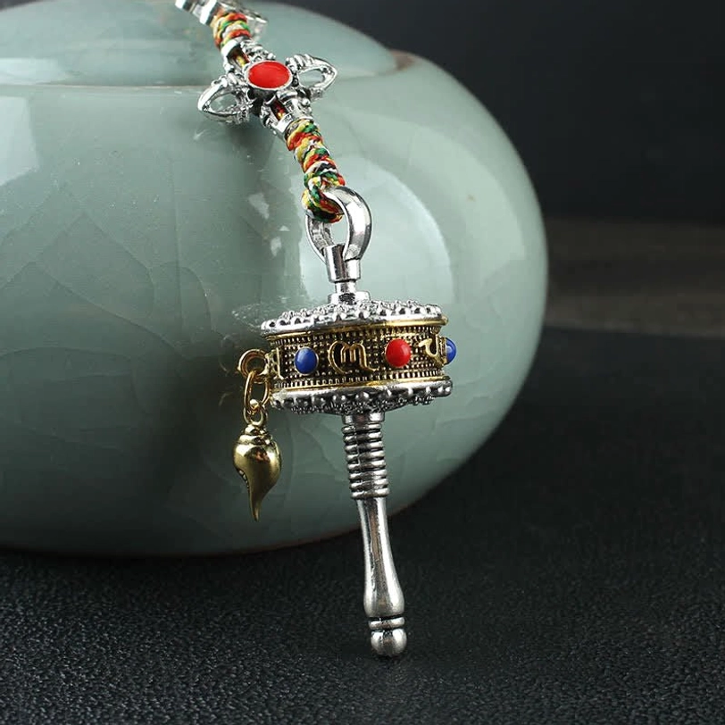 Tibetan prayer wheel car hanging decoration with rotating wheel mechanism and colorful braided rope for daily spiritual practice