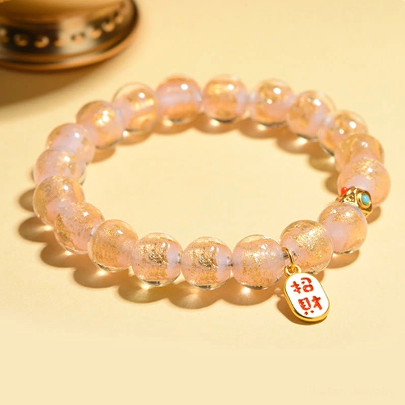 Light gold translucent incense ash glass bead bracelet with zhao cai charm on wooden table background