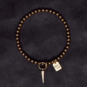 Complete overhead view of handmade copper prosperity bracelet with spike charm and good luck tag on black background