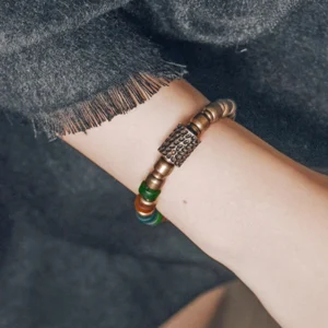 Copper glass bead bracelet worn on wrist, side view showing hammered central metal bead with elastic string and mixed beads
