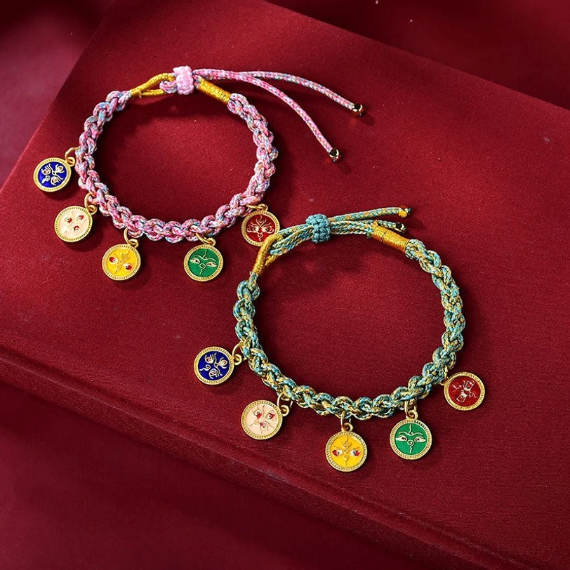 Two handmade Tibetan braided lucky bracelets in teal and pink with multiple religious enamel charms displayed together on red velvet