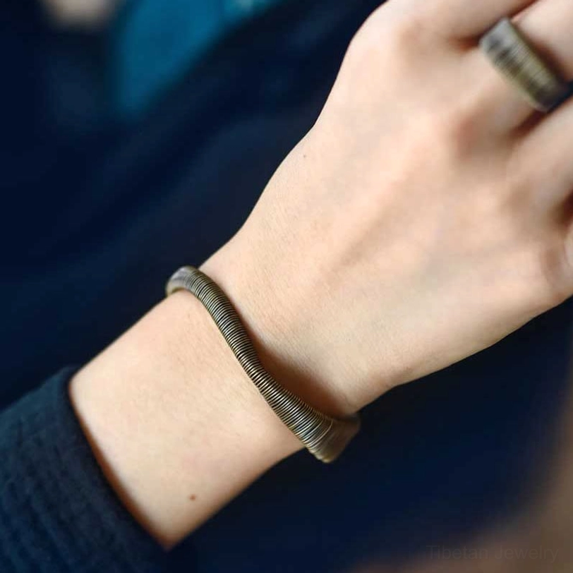 Tibetan wrapped brass prosperity cuff bracelet adjustable fit showing complete open cuff silhouette against neutral background