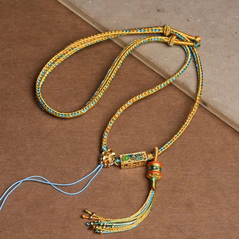 Tibetan braided copper necklace featuring gold-blue rope with rectangular enamel charm and blue beaded tassel