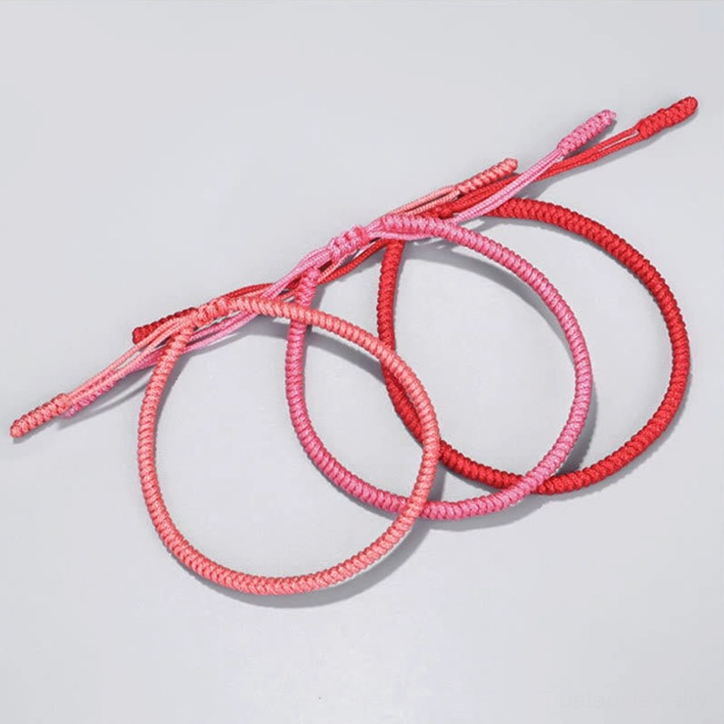 Three Tibetan braided protection bracelets in varied red shades showing simple woven design with adjustable fasteners