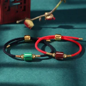 Tibetan handmade protection bracelets with green aventurine and malachite beads, red and black braided rope with gold hardware displayed on retro Chinese desktop