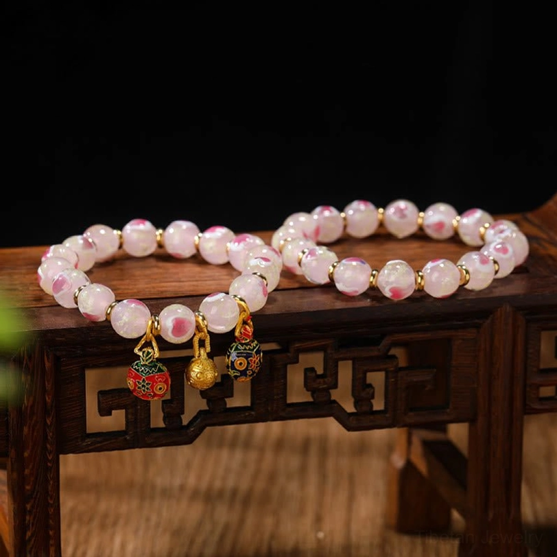 Tibetan protection bracelet with luminous pink liuli glass beads and gold beast charm detail shot