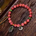Tibetan red agate camel bone protection bracelet with copper accents displayed on dark wood surface, overhead angle view
