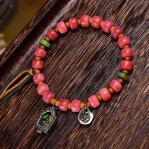 Tibetan red agate camel bone protection bracelet with copper accents displayed on dark wood surface, overhead angle view