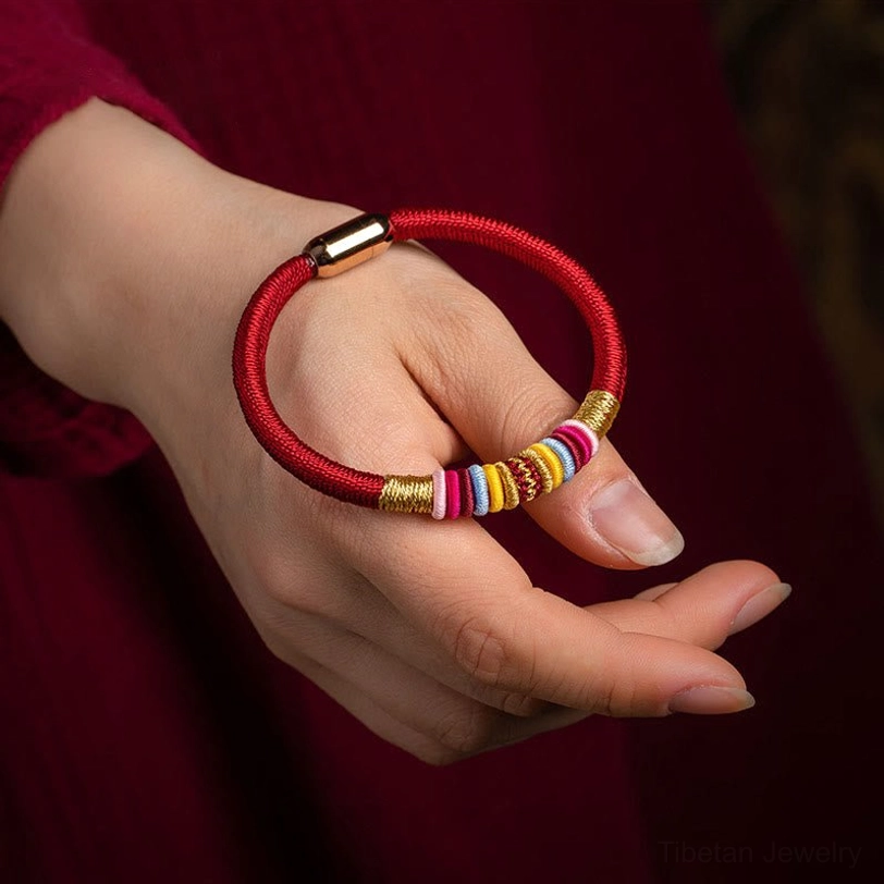 Handwoven red Tibetan Vajra Knot bracelet with magnetic clasp worn on wrist, worn on human hand