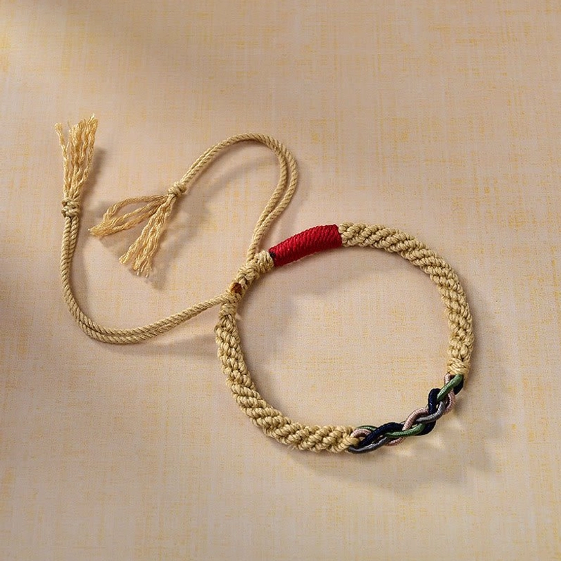 Three-quarter side view of Tibetan lucky string bracelet showing golden woven rope, red fabric band, and mixed-color decorative knot with tassels