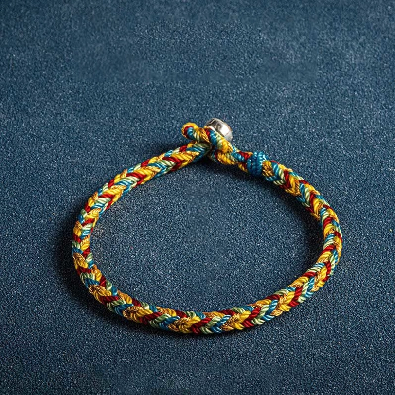 Single Tibetan multicolor lucky bracelet with red yellow blue threads and silver toggle clasp on textured dark background