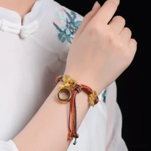 Woman wearing handcrafted Tibetan lucky bracelet on wrist, showing gold charm details and rainbow braided cord