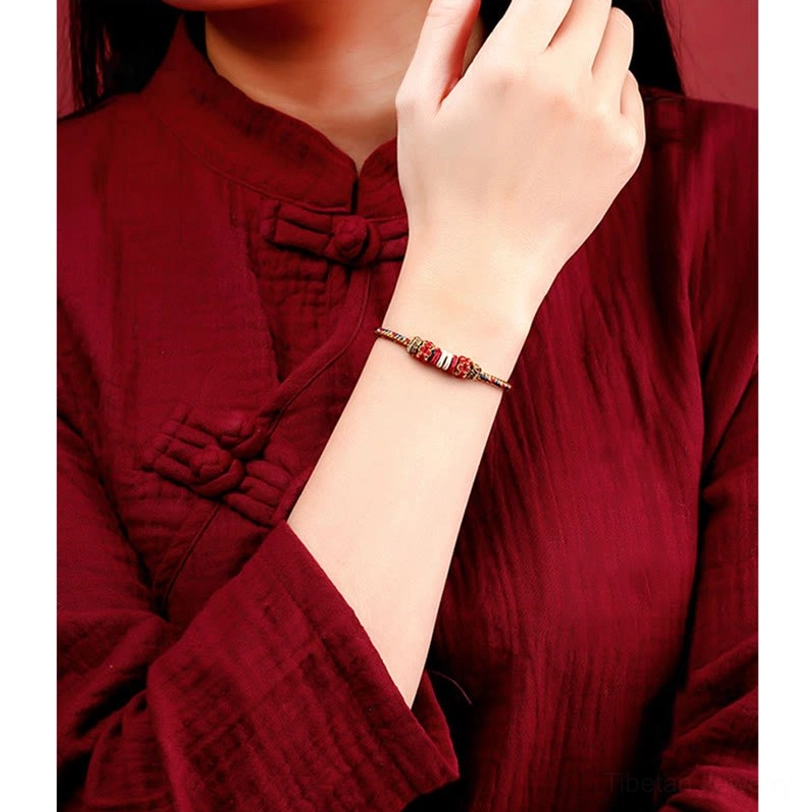 Tibetan lucky bracelet worn on wrist with traditional red fabric background