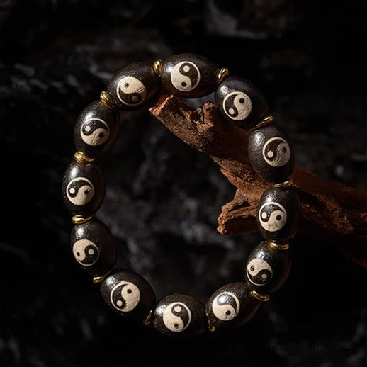 Tibetan Dzi Bead bracelet photographed on natural wood branch with stone backdrop, highlighting barrel-shaped agate beads with Yin Yang logos
