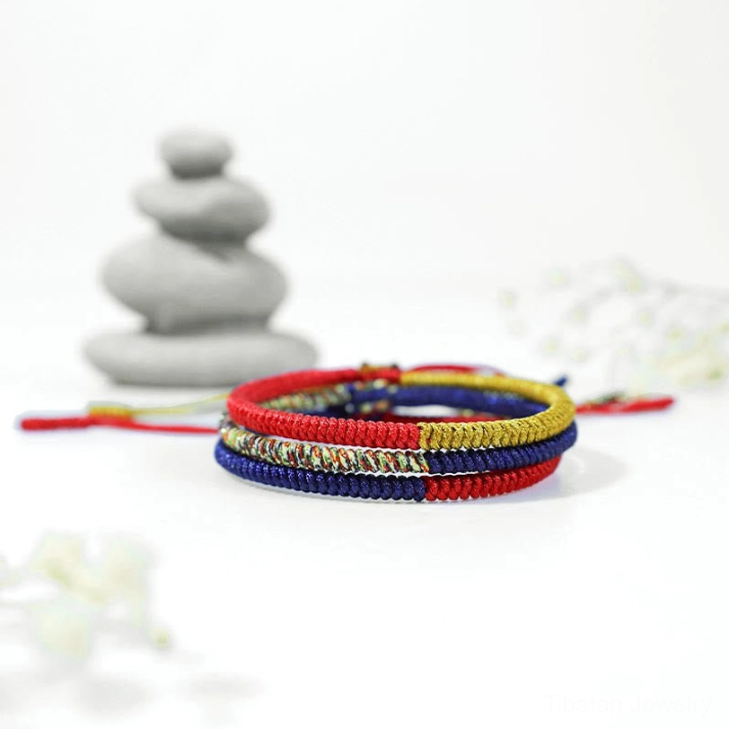 Handmade Tibetan braided wrist bracelet paired with zen stone stack decoration on meditation background
