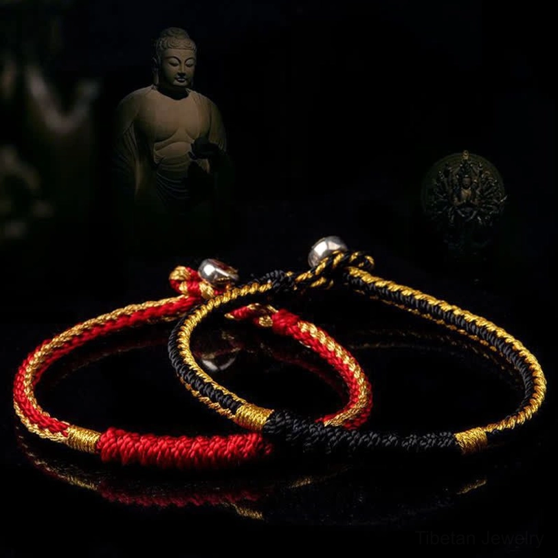 Two Tibetan handmade braided bracelets in red-gold and black-gold, top-down view with Buddha statue background