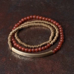 Red agate beads with bronze brass components Tibetan triple wrap bracelet flat lay on rustic surface