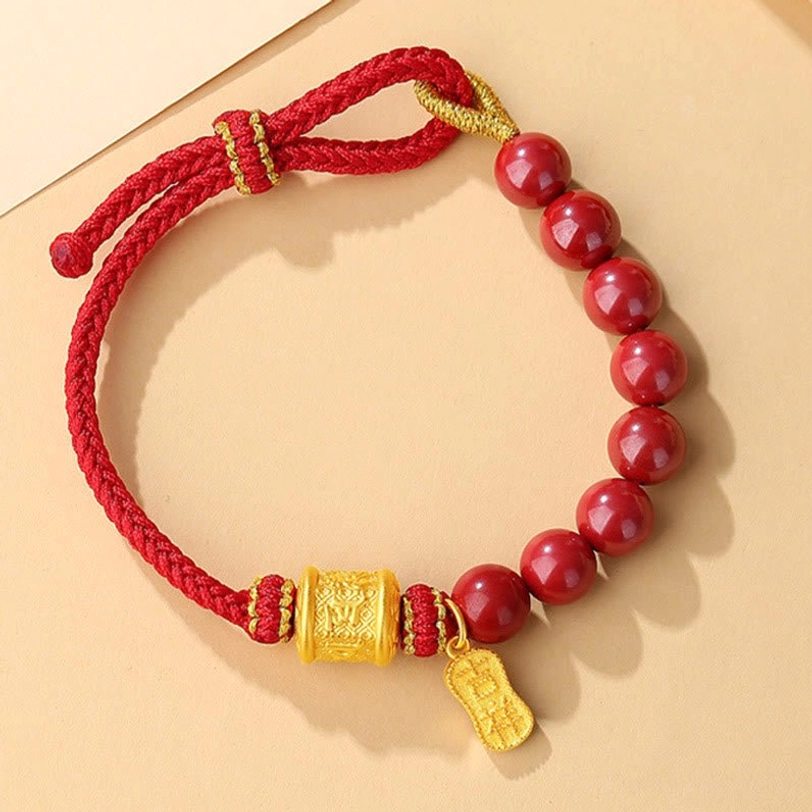 Cinnabar red rope bracelet with sliding adjustable knot and prayer bead charm on light neutral tabletop