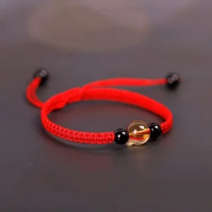 Red string Tibetan protection bracelet with citrine and obsidian beads, side view showing traditional knot design