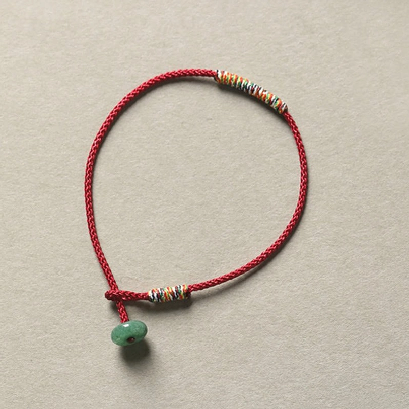 Red braided Tibetan luck bracelet with colorful woven wraps and green aventurine donut charm pendant