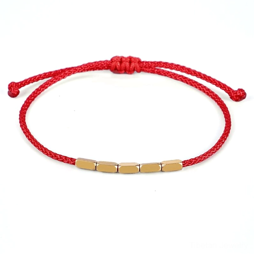 Red Tibetan copper bead protection bracelet with handwoven cord and sliding knot adjuster, flat lay overhead view on white background