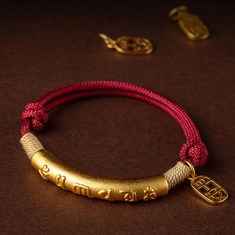 Red woven cord Tibetan blessing bracelet with gold metal charm detail and extra charms displayed